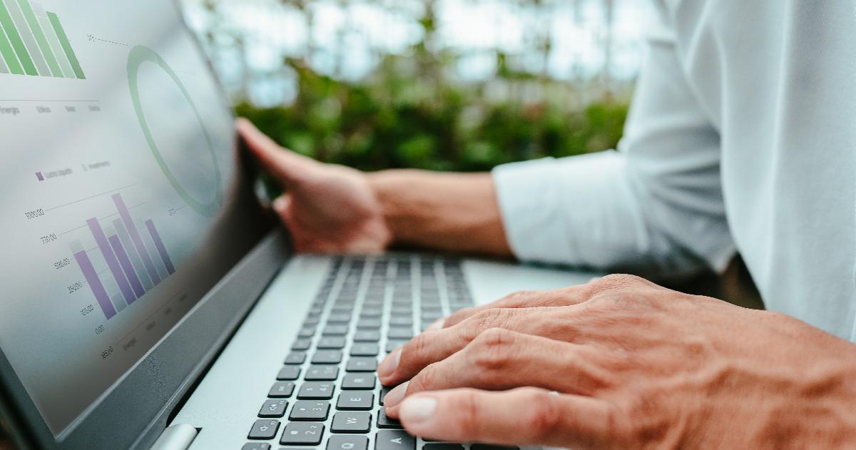 Hands of person holding laptop with graphs and tables on laptop screen