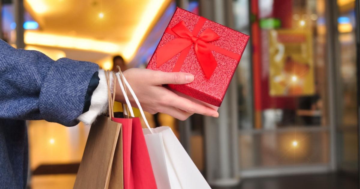Person's hand holding a gift with other bags hanging from wrist