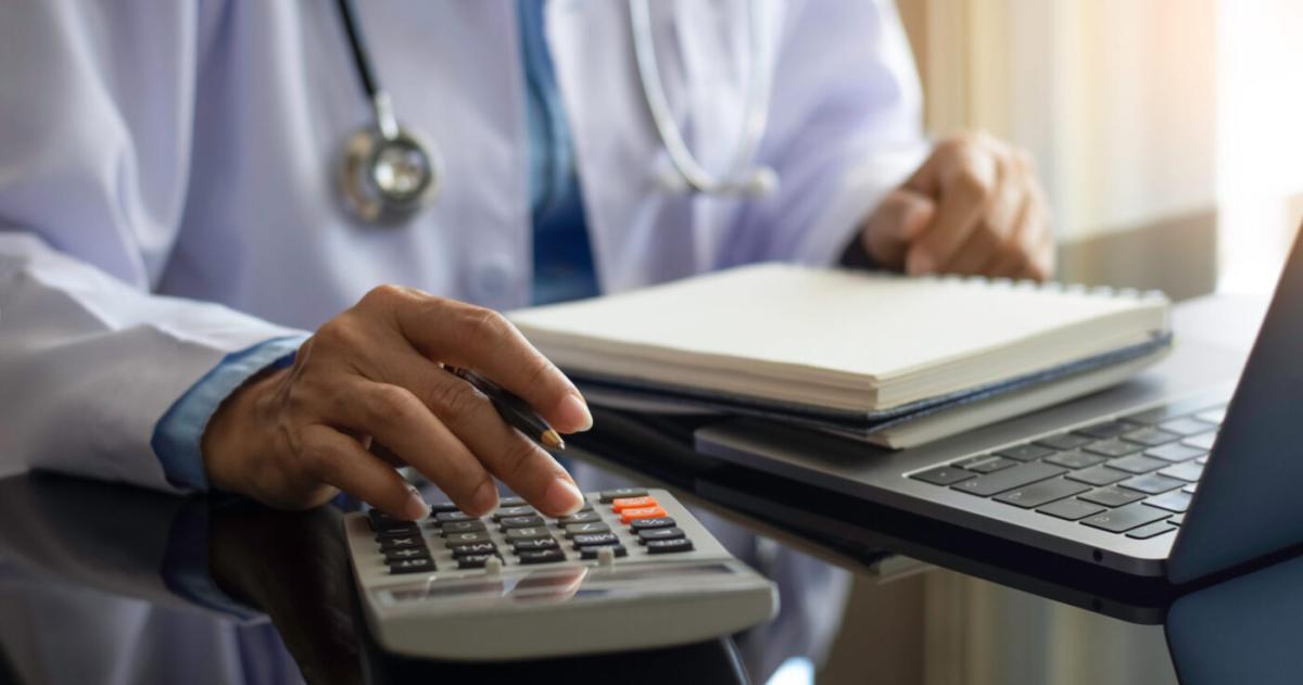 Doctor using a calculator with stethoscope around neck