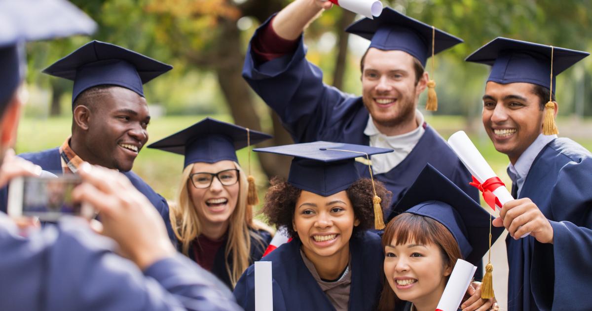 Group of college graduates in caps and gowns having their picture taken
