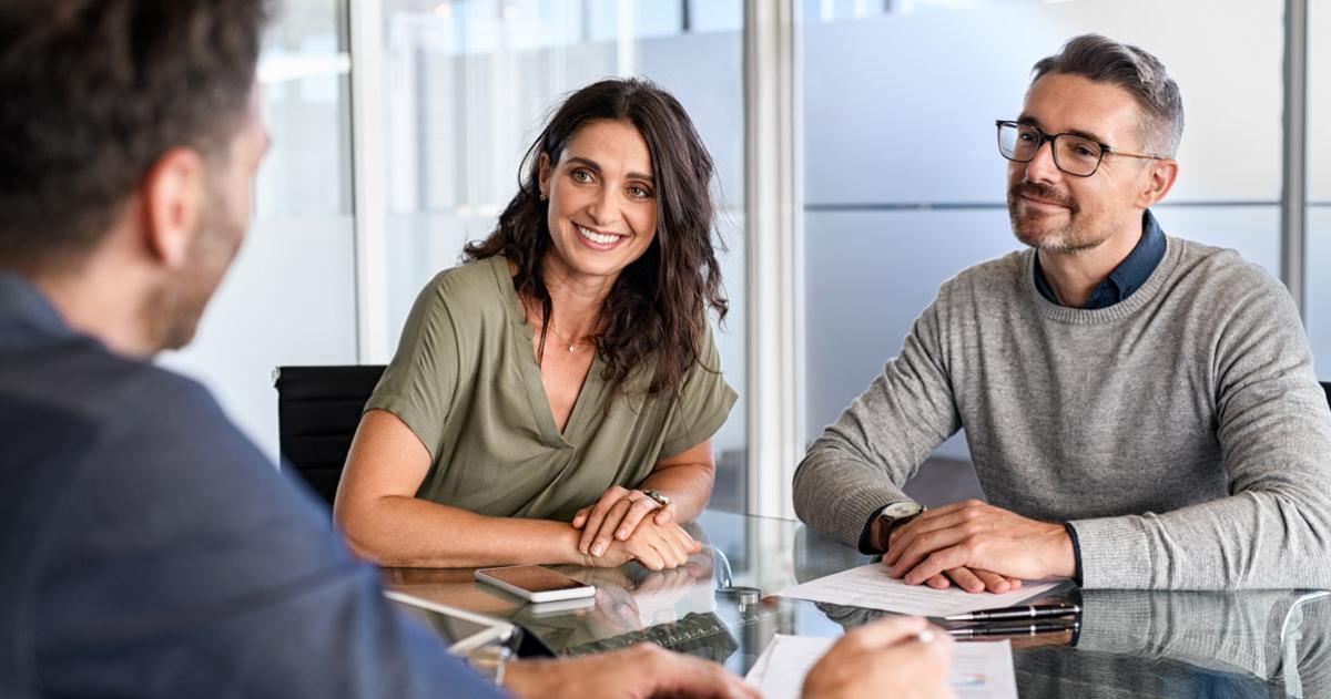 Woman and man sitting at conference table talking to an advisor