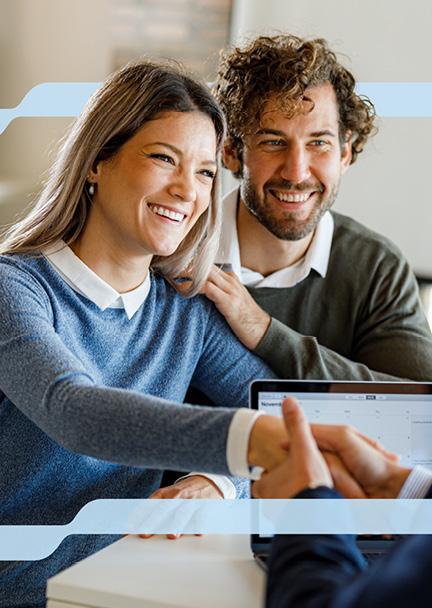 A couple sitting down smiling and shaking an advisors hand