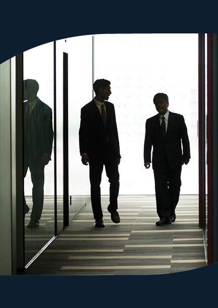 Two men walking down a dramatically lit hallway