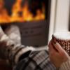 Fireplace with the lower half of a person in pajamas holding a mug.