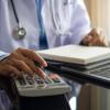 Doctor using a calculator with stethoscope around neck