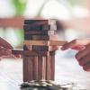 Two hands pulling blocks from Jenga tower