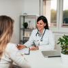 Female doctor behind a desk speaking to a female patient