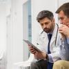Physician and a man reviewing something on an tablet