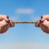 Two hands pulling a rope in opposite directions