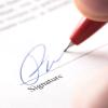 Hand with pen signing legal document