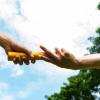 Close up of the hands of two runners passing a metal baton in a relay race