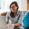 Woman sitting on couch typing on laptop