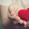 Two hands holding a crocheted heart 