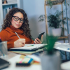 Woman sitting at a desk with a notepad, pencil and phone
