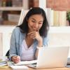 Young woman with notepads looking at laptop