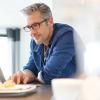 Man in blue shirt and glasses working on laptop