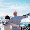 Rear view of older man and woman with arms around each other out in nature