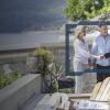 A couple shaking the hand of an advisor at a villa by the lake