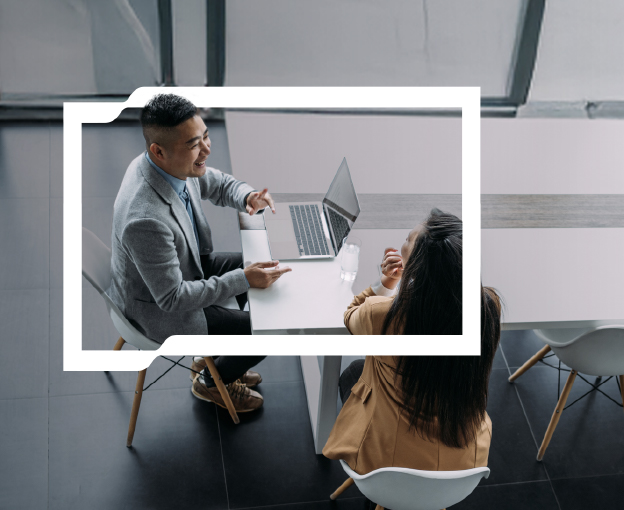 A man at a laptop talking to a woman